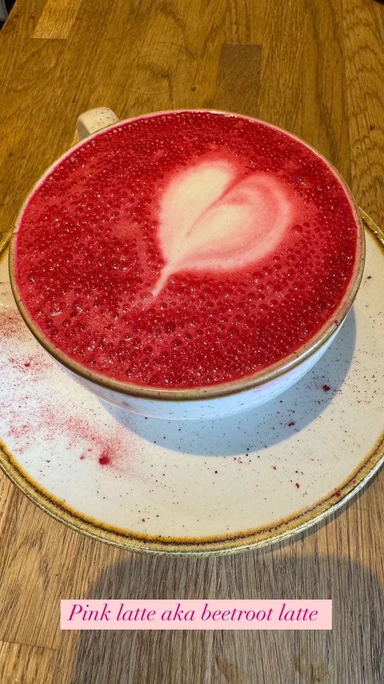 A beetroot latte with heart latte art in a blue cup, from above
