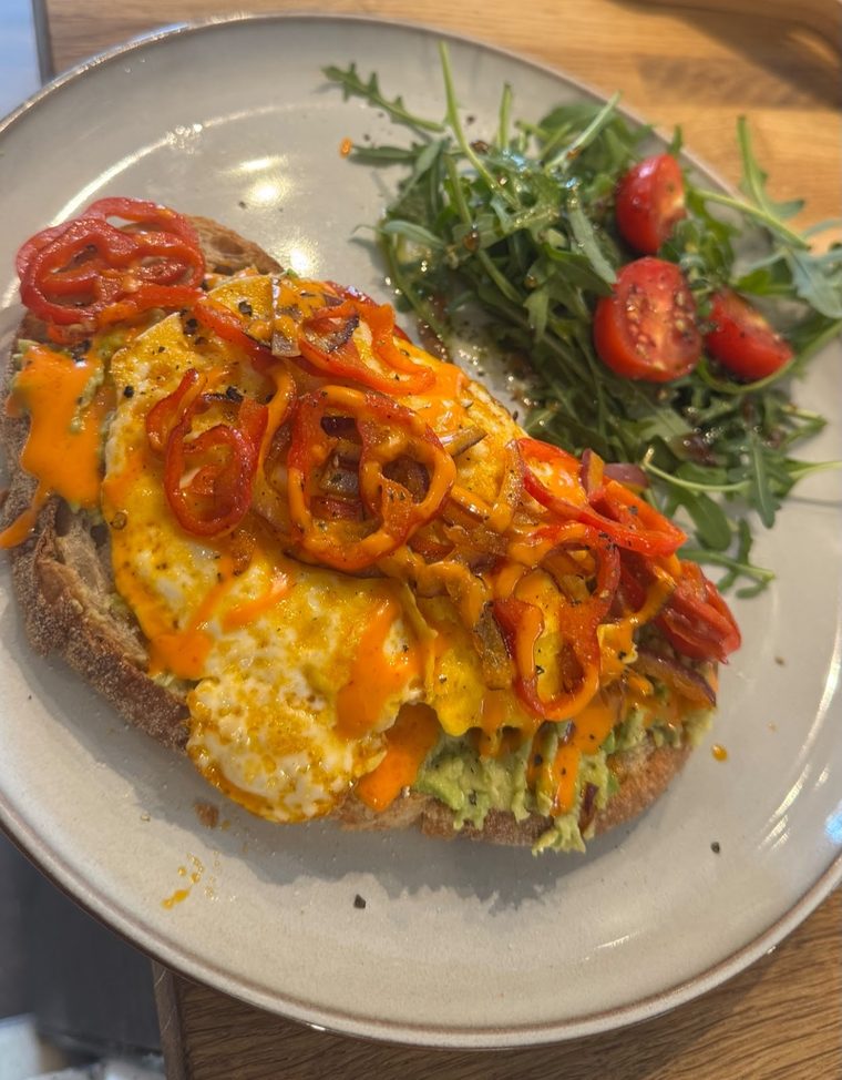 Loaded toast with egg, cheese and peppers alongside rocket and tomatoes